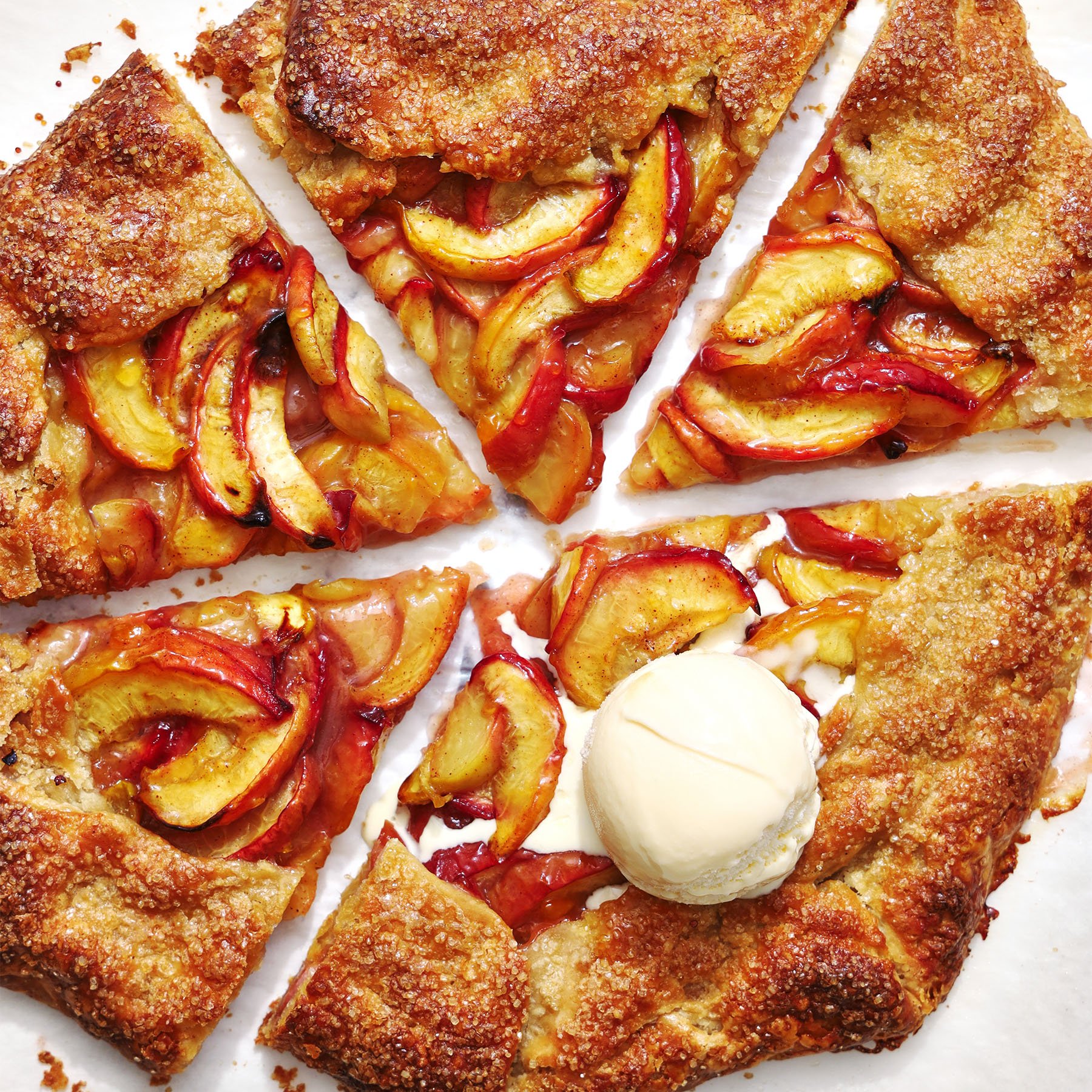 sliced peach galette with a scoop of vanilla ice cream on top