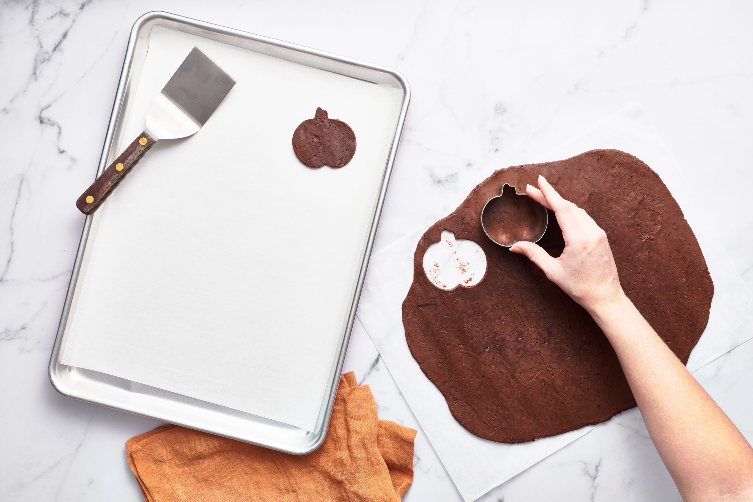 baking tray with a pumpkin shape cut out of the chocolate sugar cookie dough.