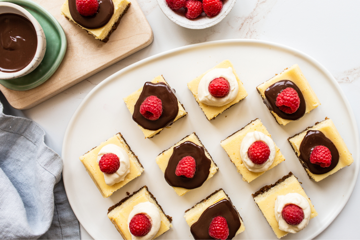 slices of cheesecake bar with a variety of toppings, like ganache and fresh raspberries. 