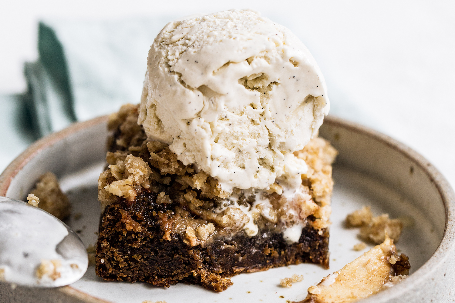 Easy non-pie dessert option for Friendsgiving: Apple Crisp Cookie bar on a plate, with a scoop of vanilla ice cream on top.