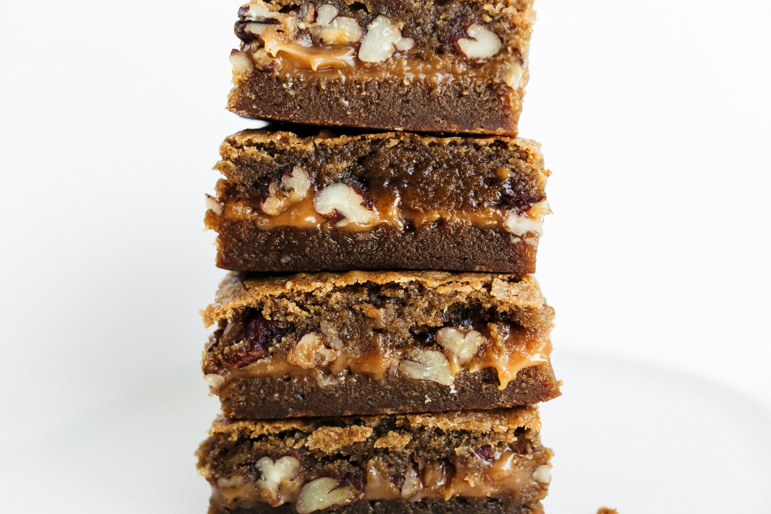 several caramel pecan blondies stacked on top of each other.