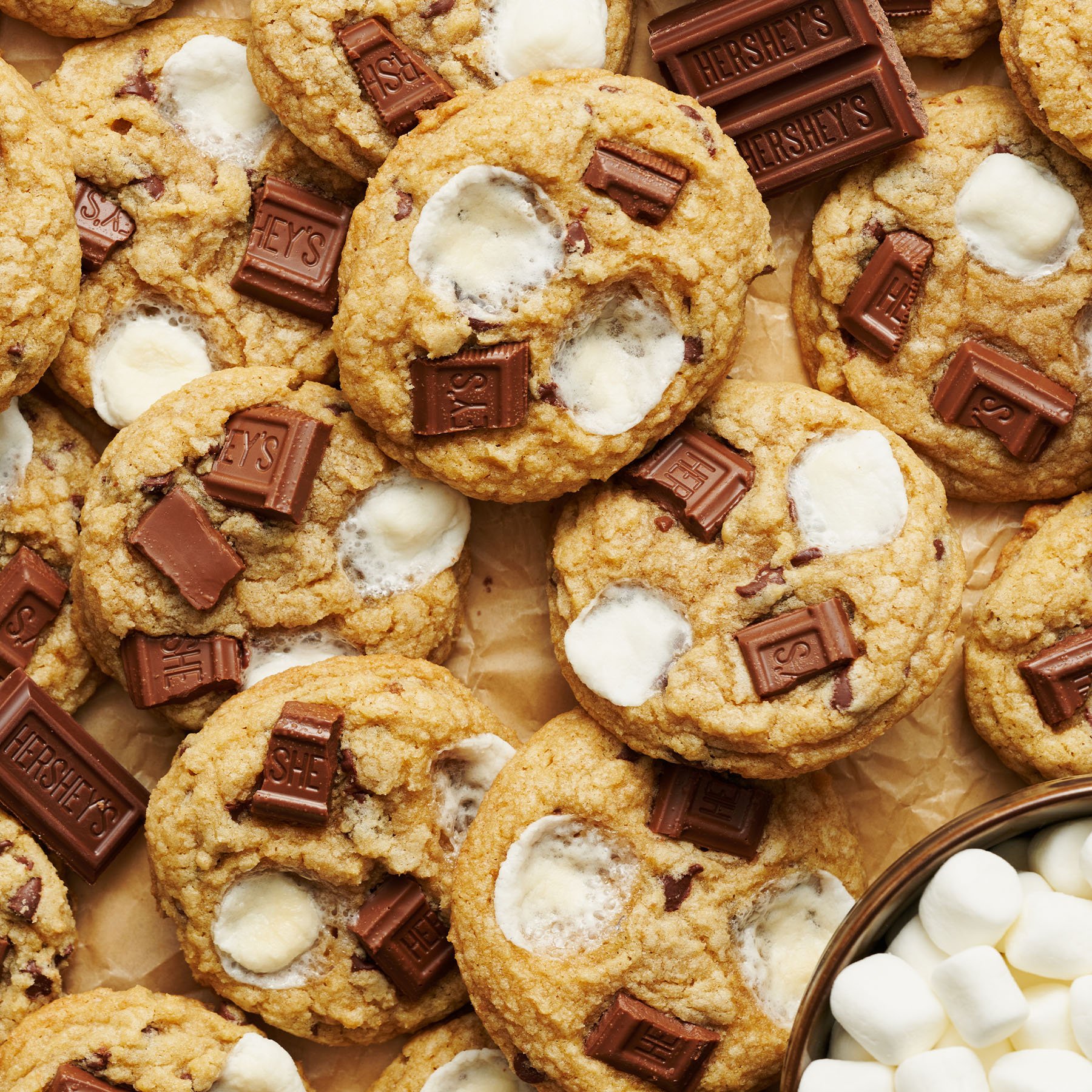 smores cookies topped with mini marshmallows and Hershey's chocolate bar pieces