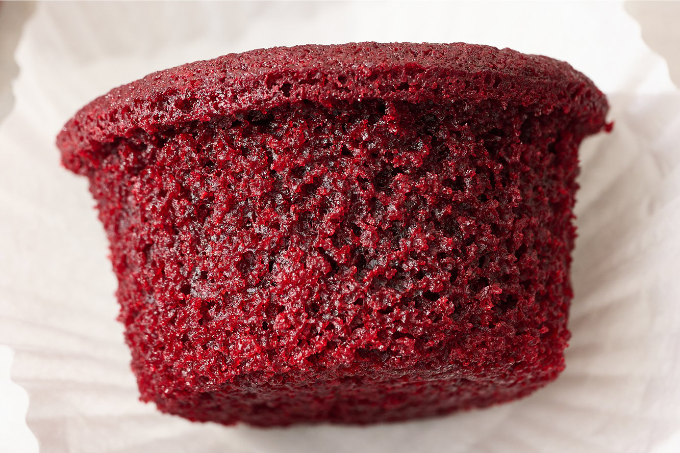close up of one red velvet cupcake with its wrapper removed, before being iced and served.
