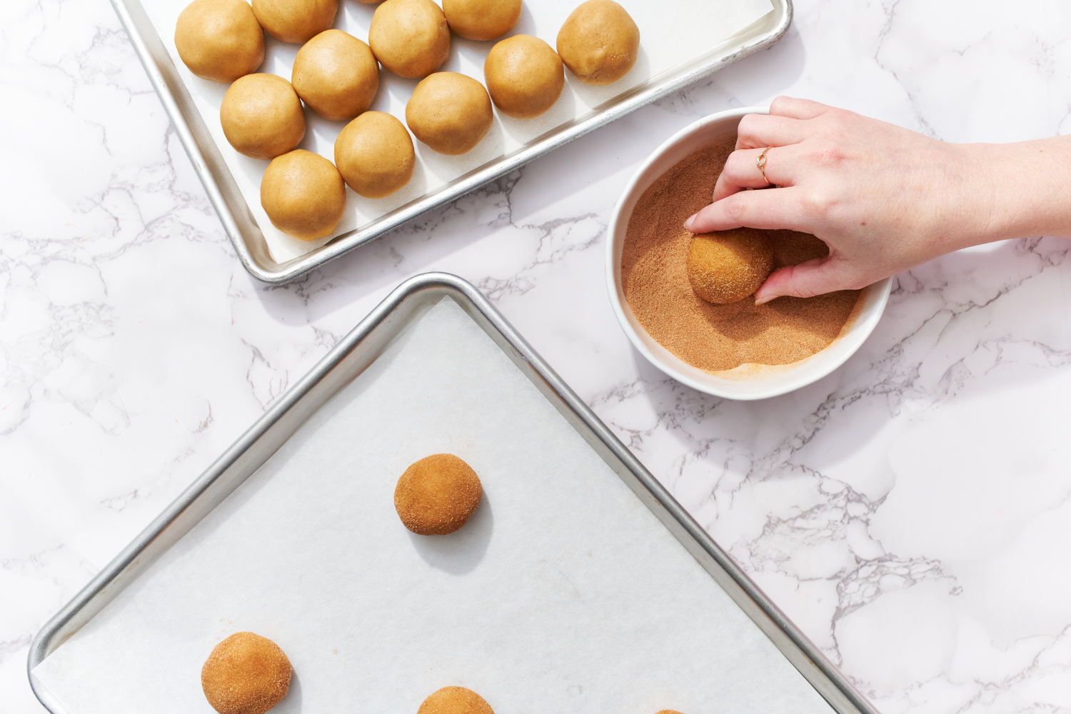 rolling the cookie dough balls in cinnamon sugar.