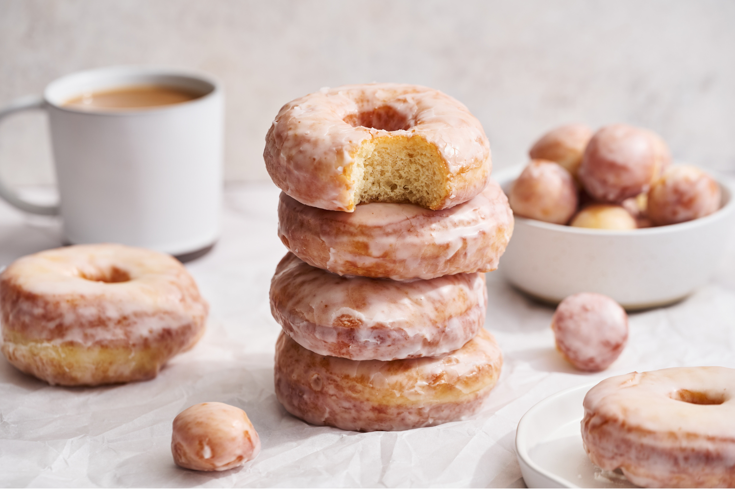 a stack of donuts next to a cup of coffee.