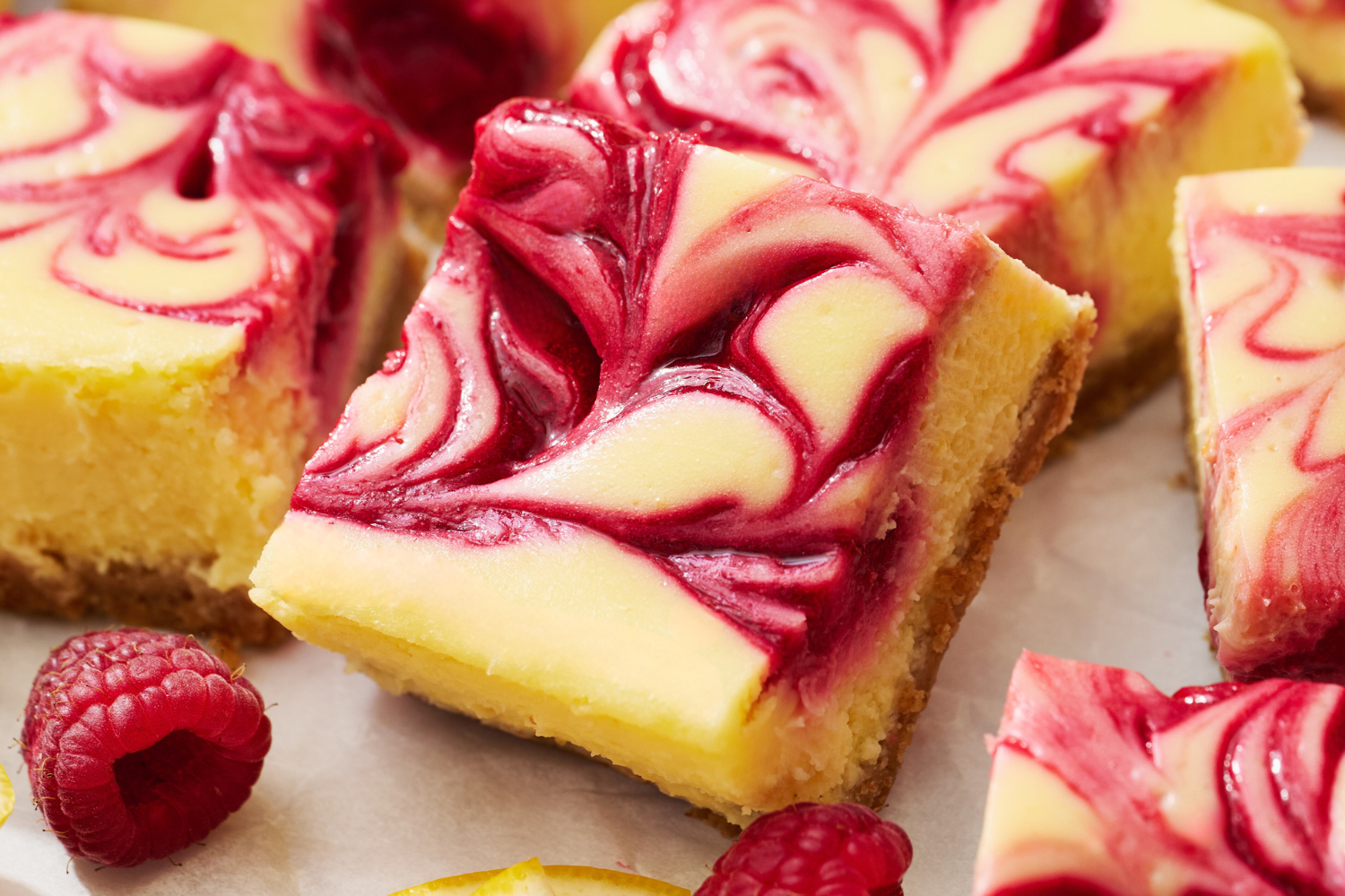 slices of raspberry lemonade cheesecake bars on a white countertop.