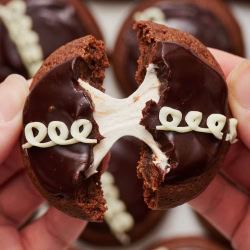 a hostess cupcake cookie broken in half and being pulled apart, with gooey marshmallow pulling between the two cookie halves.