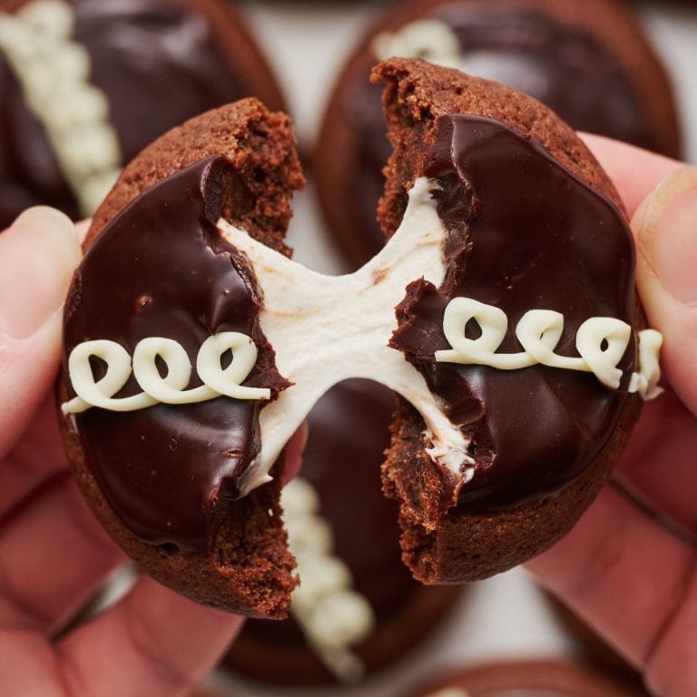 a hostess cupcake cookie broken in half and being pulled apart, with gooey marshmallow pulling between the two cookie halves.