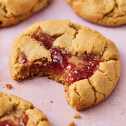 a peanut butter and jelly cookie with a bite taken out.
