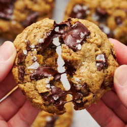 a warm Bourbon Rye Oatmeal Chocolate Chunk Cookie being pulled apart, with gooey chocolate between the two halves.