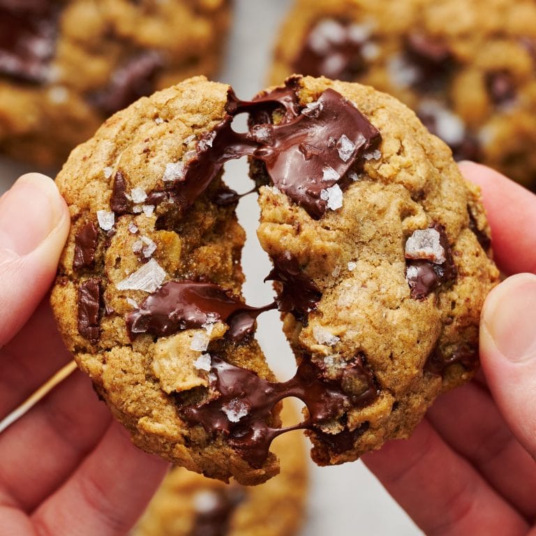 a warm Bourbon Rye Oatmeal Chocolate Chunk Cookie being pulled apart, with gooey chocolate between the two halves.
