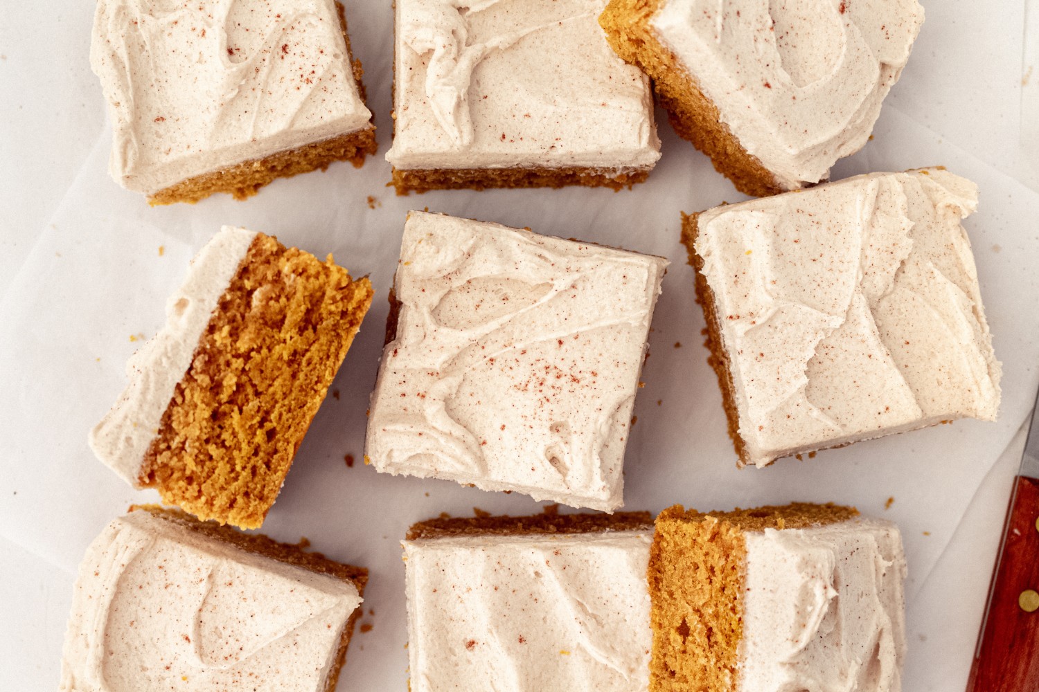 slice of pumpkin bars with brown sugar frosting on a white backdrop.