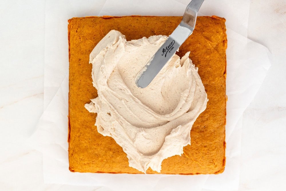 baked pumpkin bars with brown sugar frosting being spread on top