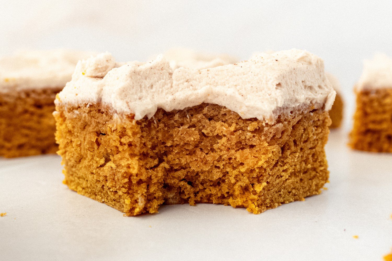 a pumpkin bar with frosting with a bite taken out.