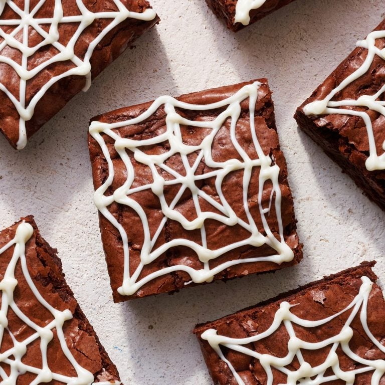 a slice of brownie with a white chocolate spider web piped on top, for the ultimate halloween brownie.