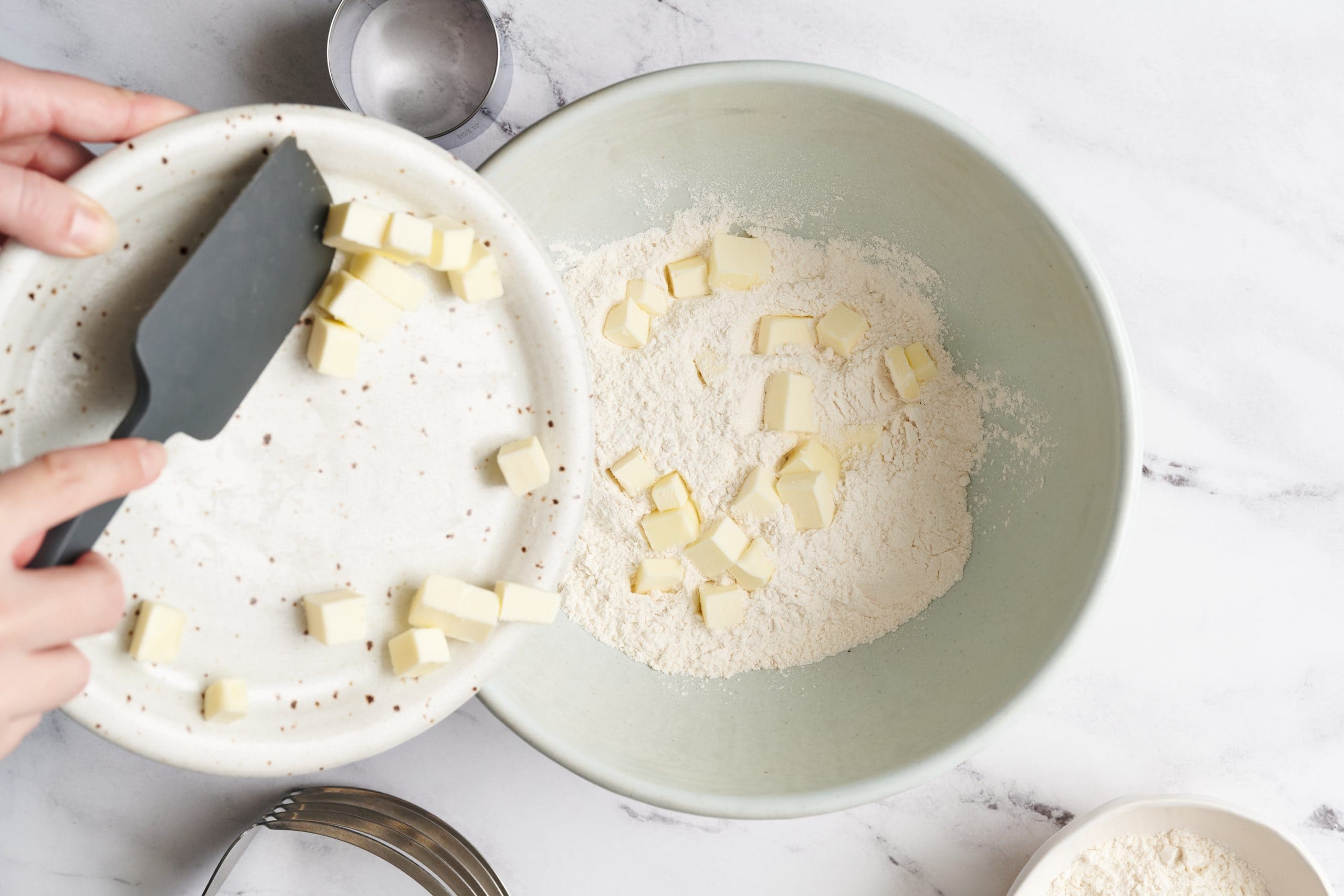 cubed butter being added to butter to mix for buttermilk biscuits