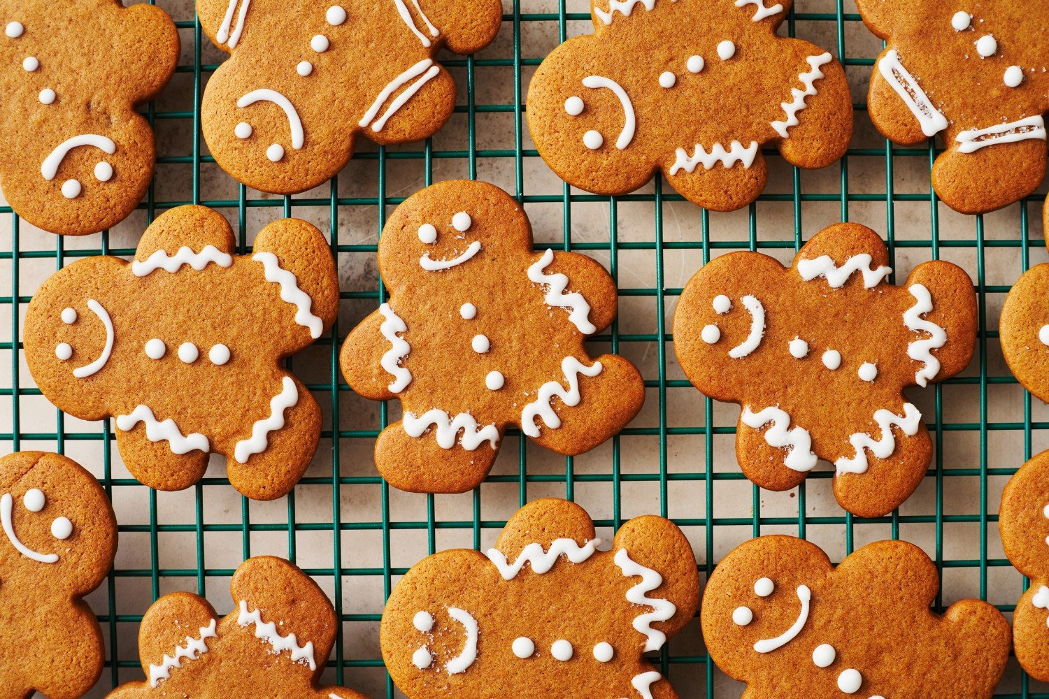 gingerbread cookies on a wire cooling rack after being decorated with a simple white icing.