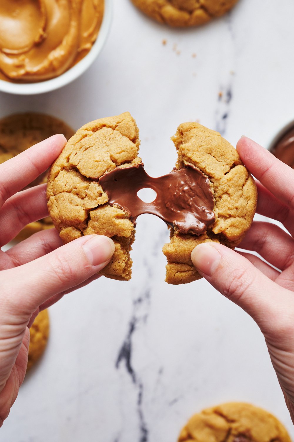 a single cookie being pulled apart with gooey nutella pulling between the two cookie halves.