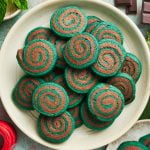 several mint chocolate pinwheel cookies on a white plate.