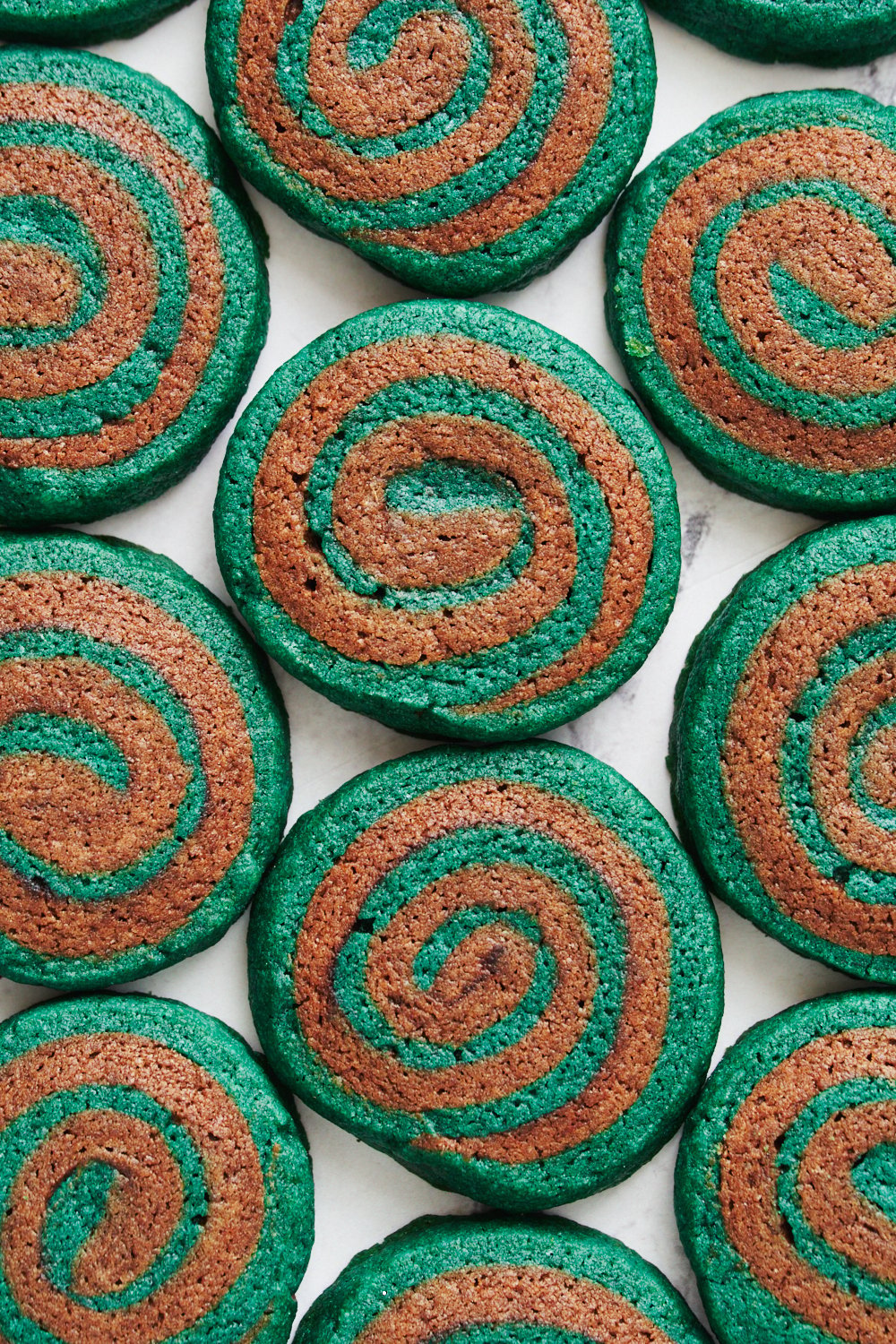 several chocolate pinwheel cookies laying flat on a plain white background.