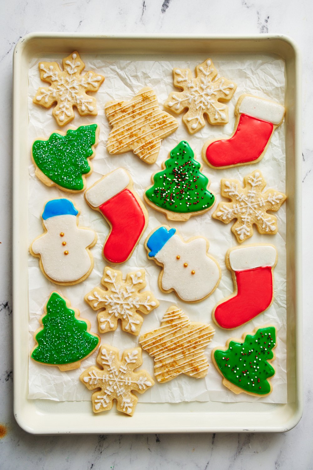 a baking tray of sugar cookies with icing.