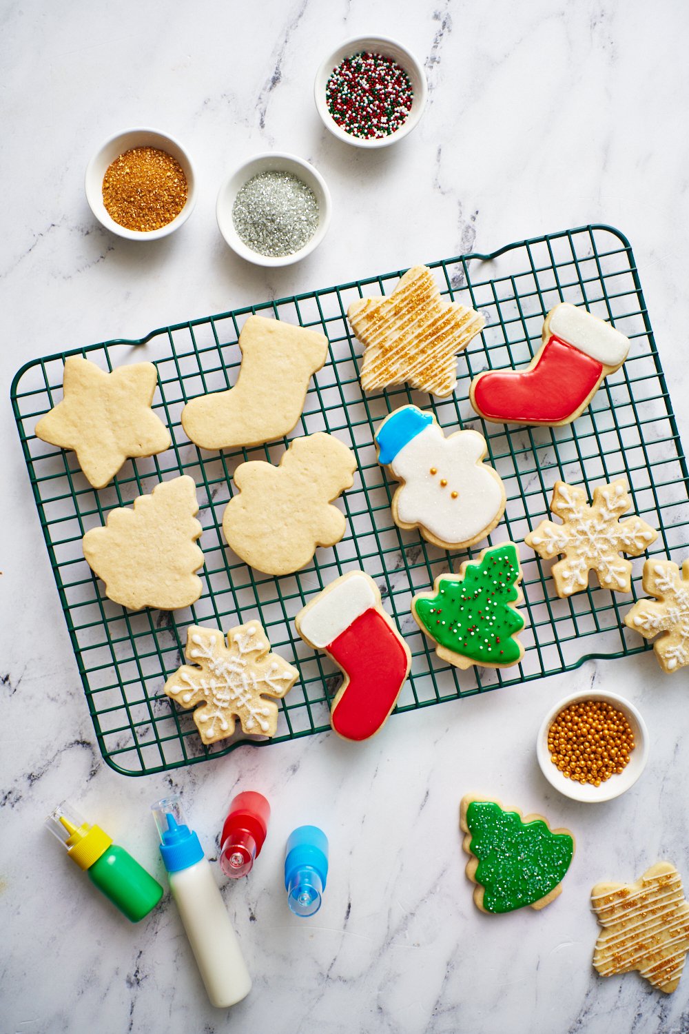 a cooling rack with sugar cookies on top, some iced and some without icing.