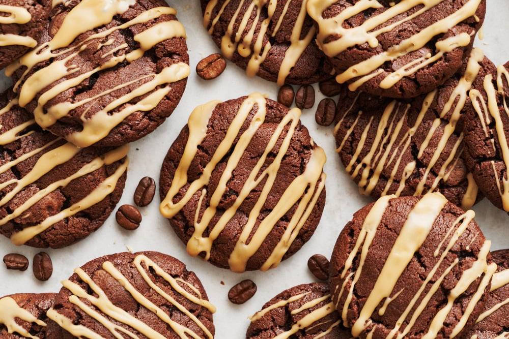 a batch of espresso martini cookies scattered on a marble background, with coffee beans around the cookies.