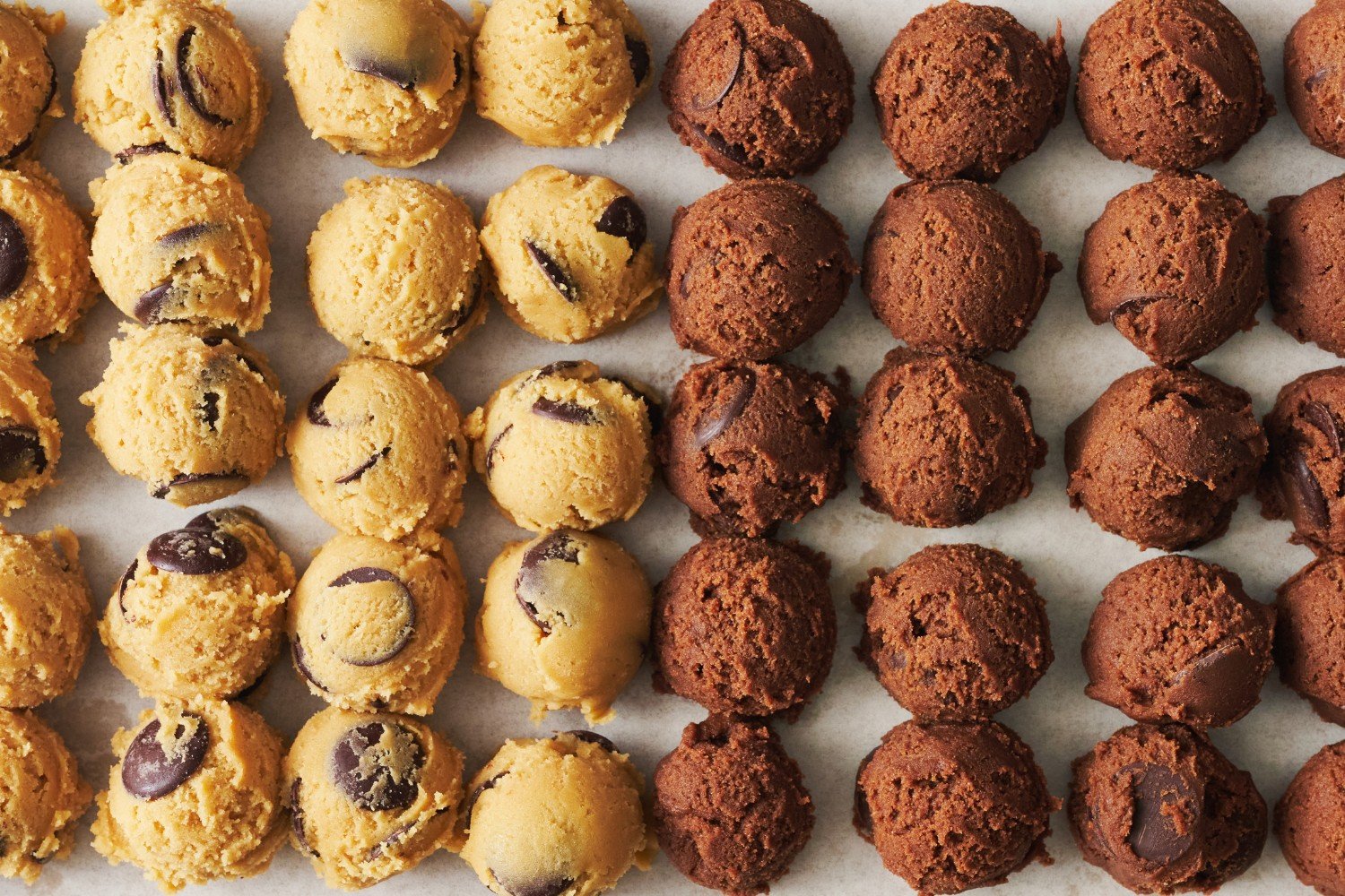 balls of portioned cookie dough lined up on a baking tray. 