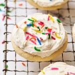 Lofthouse Cookies with white icing and rainbow sprinkles on a cooling rack.