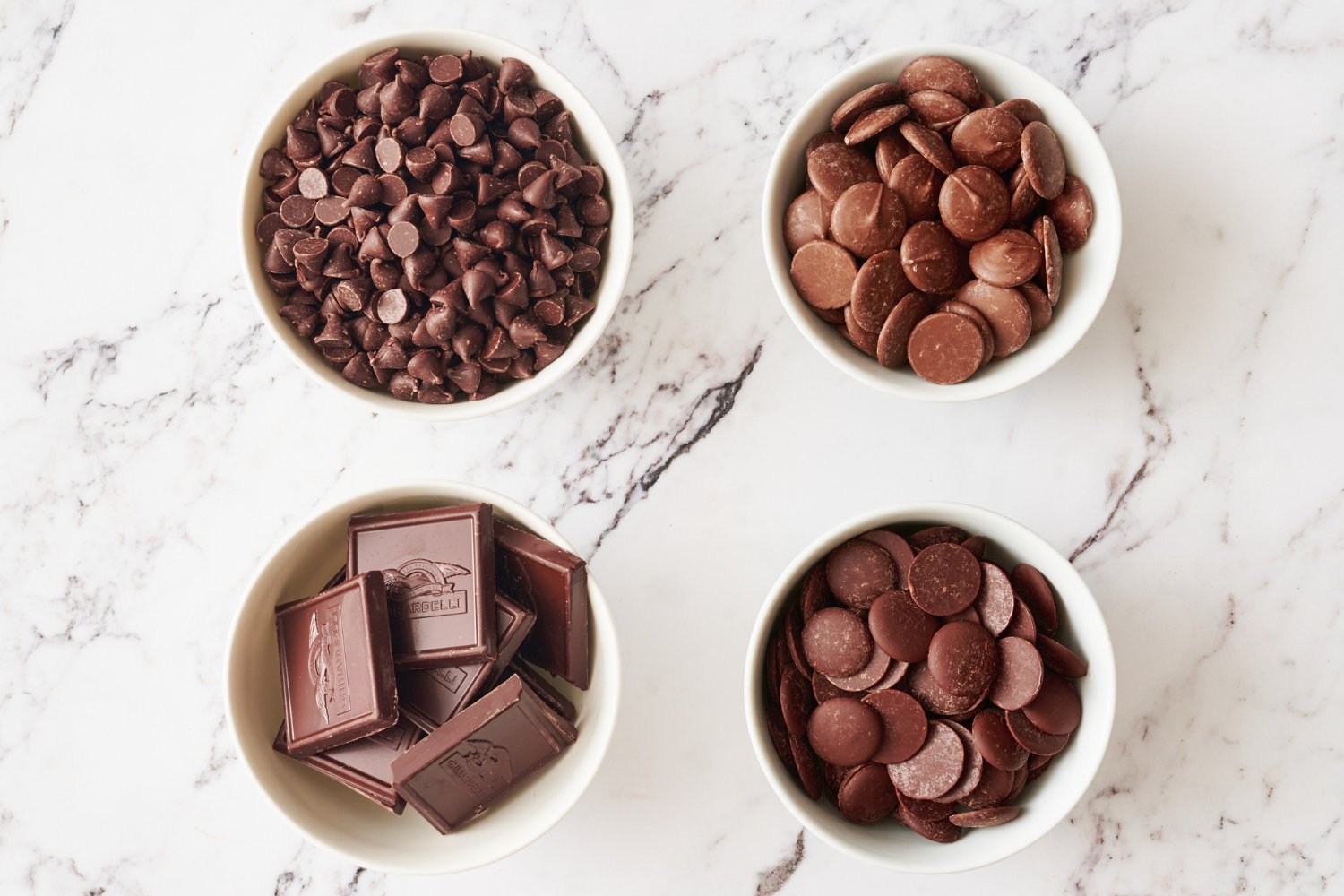 four bowls of different types of chocolate for baking. 