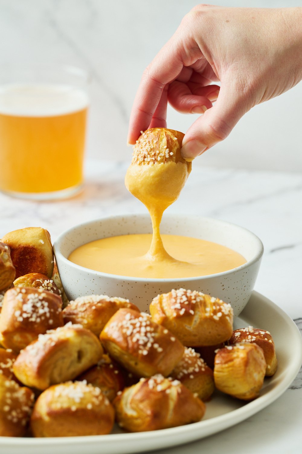 a soft pretzel bite being dipped in beer cheese dip.