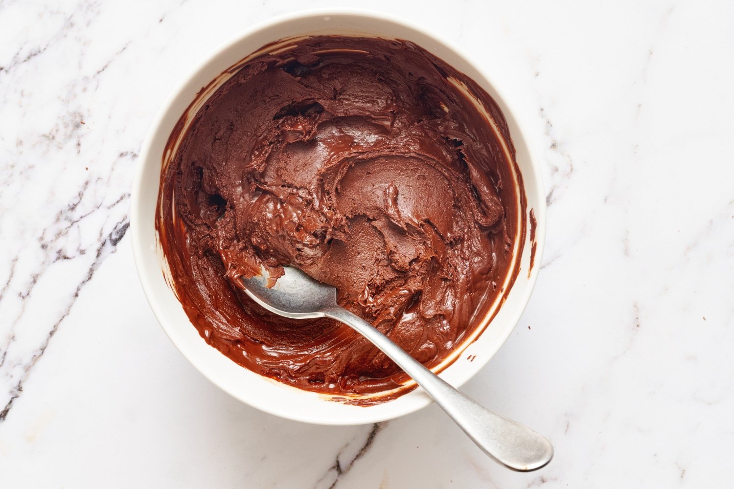 a small bowl of seized chocolate with a spoon. 