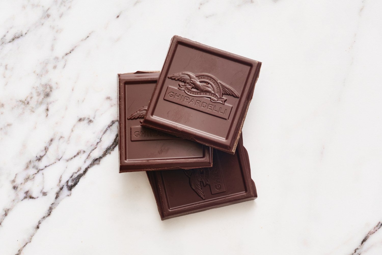 a few pieces of unsweetened chocolate on a marbled surface. 