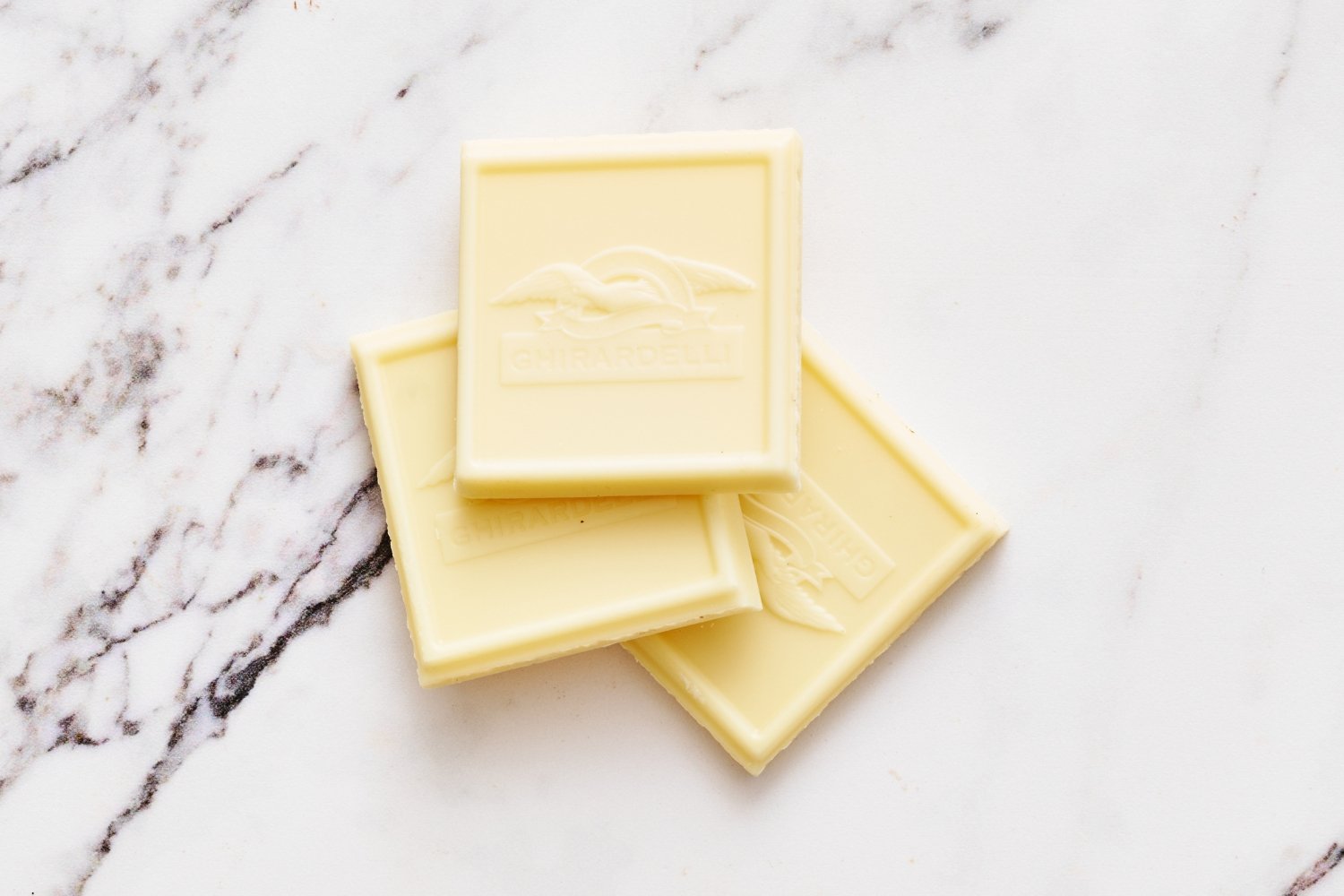 a few pieces of white chocolate on a marbled surface. 