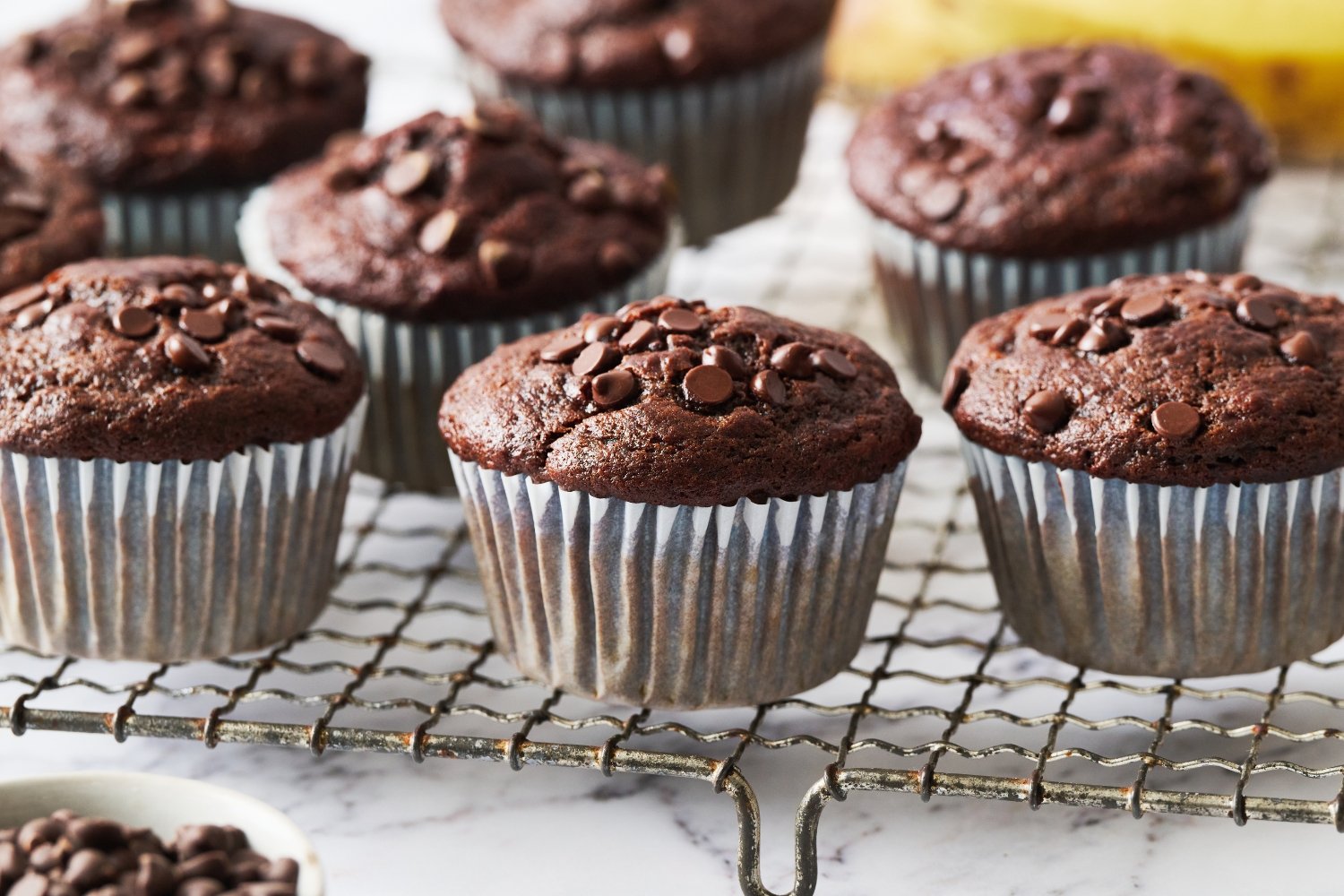 several double chocolate banana muffins on a wire rack.