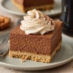 a slice of Chocolate Stout Cheesecake Bars with whipped cream, on a plate.