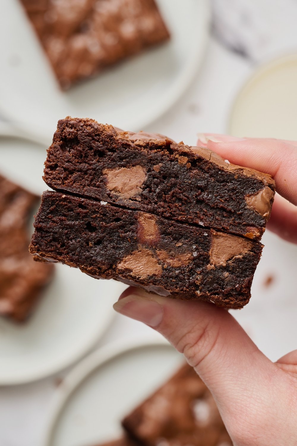 a hand holding two fudgy Malted Brownies.