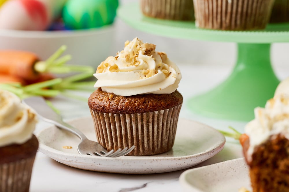 a carrot cupcake on a plate with a fork, ready to serve.