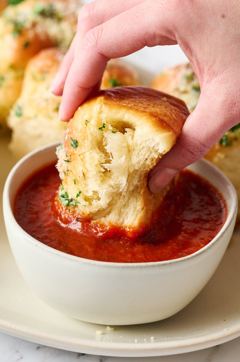 a knot being dunked in marinara sauce.