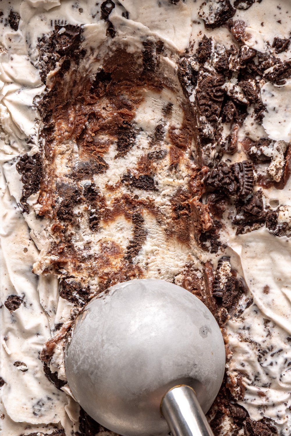 scooping cookies and cream ice cream from container