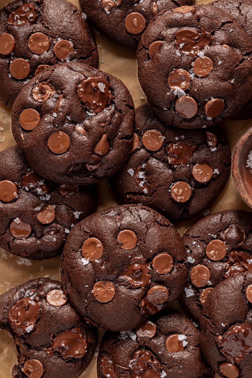 overhead view of many chocolate cookies on a tray sprinkles with sea salt