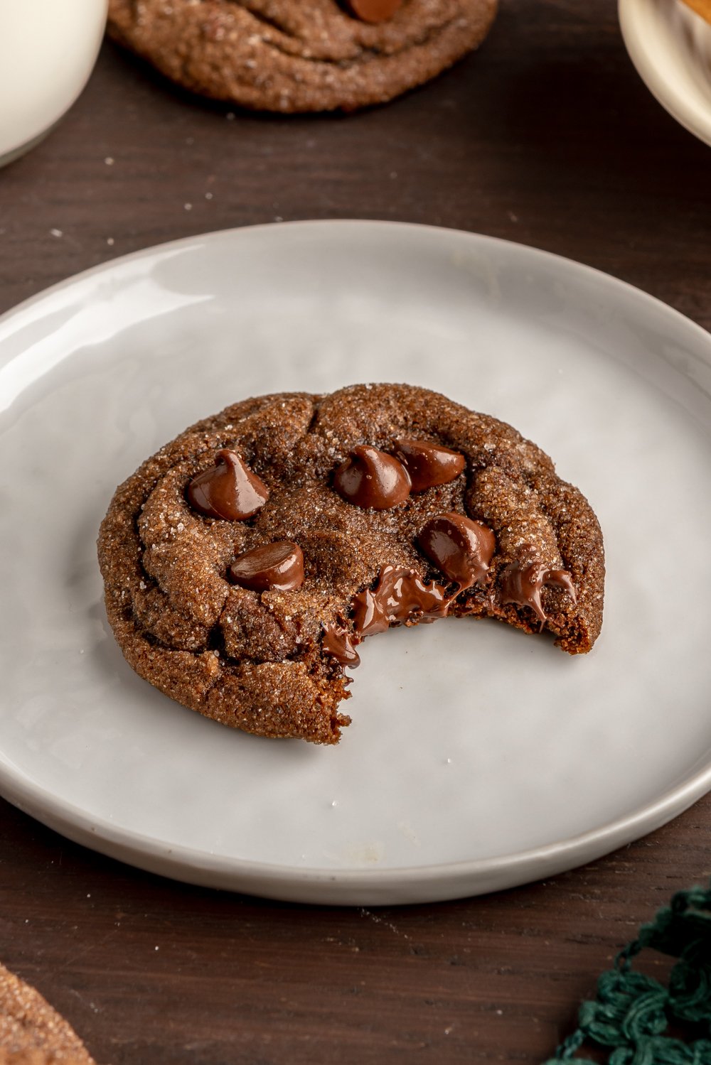 one cookie on a small plate with a bite taken out to show gooey chocolate inside