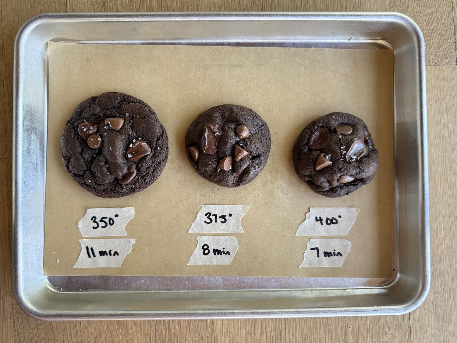 overhead shot of three cookies baked at different temperatures, showing how the cookie becomes thicker at higher temperatures