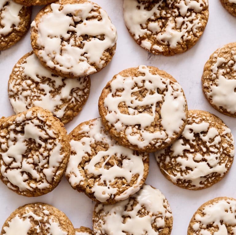 many iced oatmeal cookies on a marble countertop