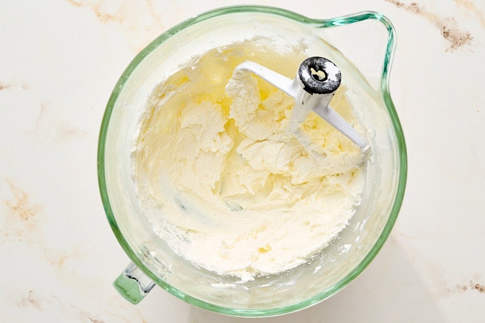 overhead view of butter and sugar creamed in a glass mixing bowl for sugar cookies