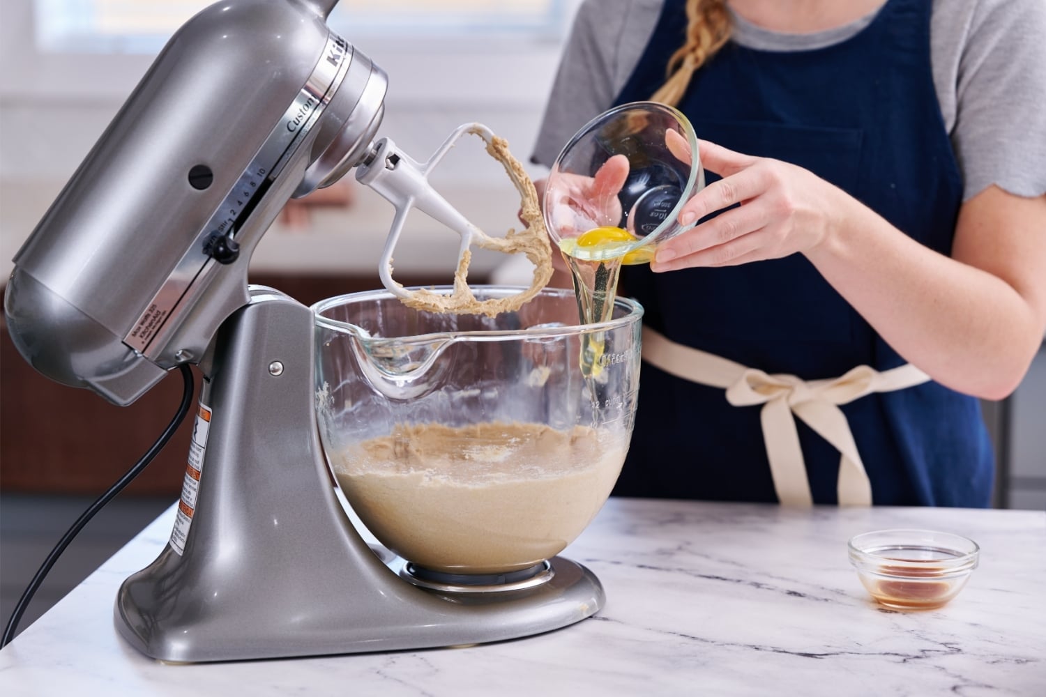 Tessa adding eggs to mixing bowl
