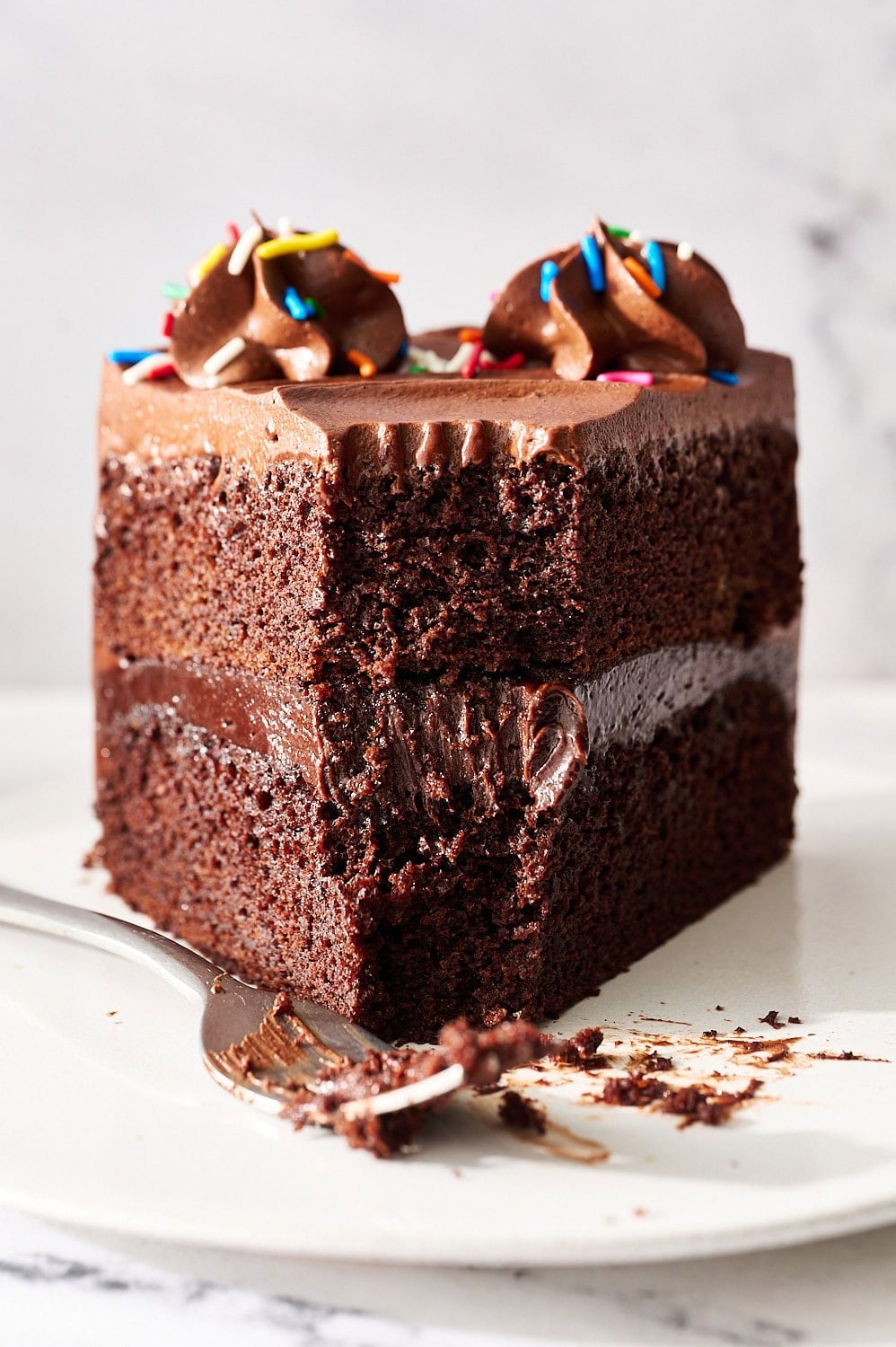 slice of fudgy chocolate cake on a small plate with a fork and a bite eaten