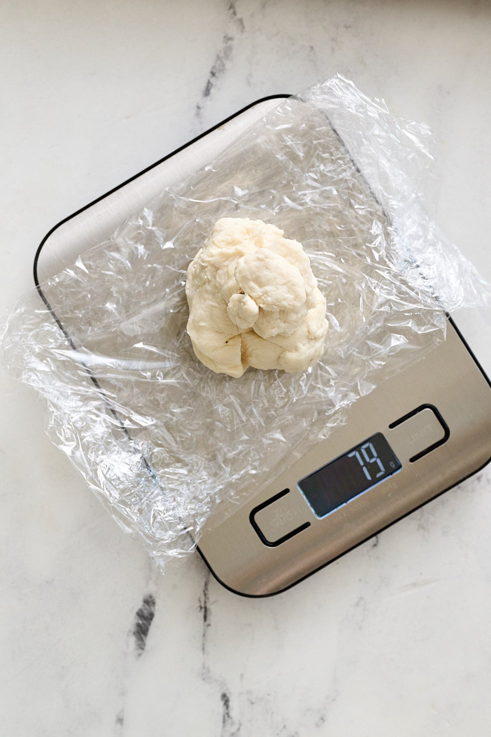 overhead view of a digital scale with a ball of pretzel dough on top being weighed