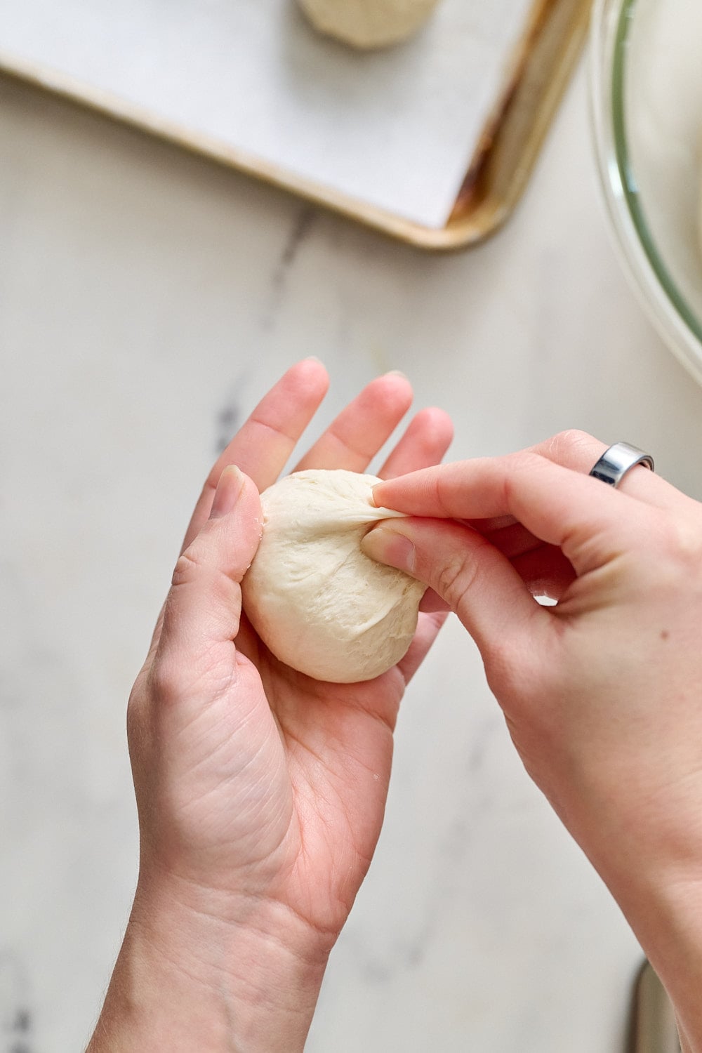 hands holding a ball of dough, shaping into a tight ball