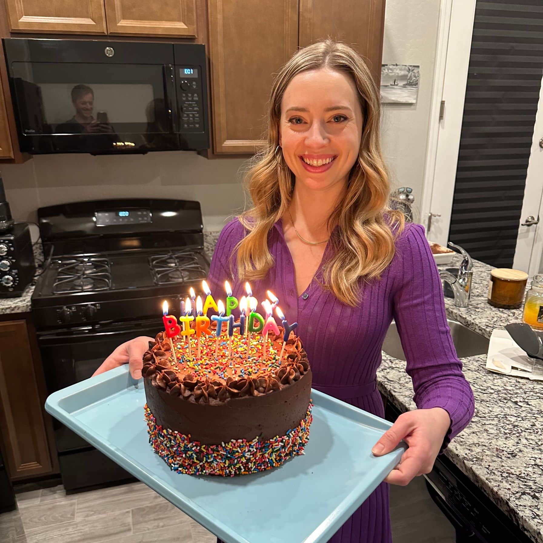 Tessa holding a chocolate cake with "Happy birthday" candles on top